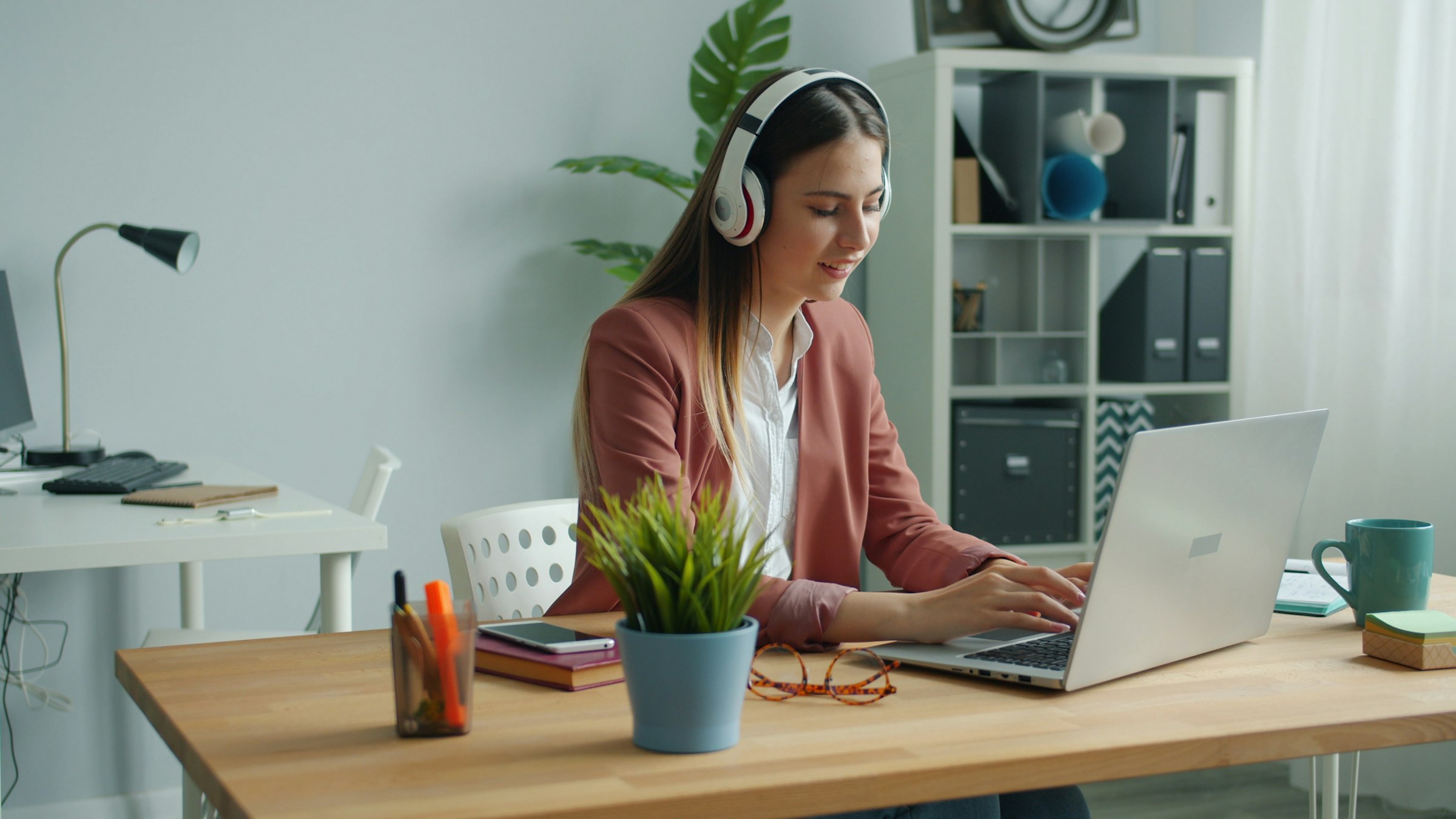 A learner wearing headphones completing an online English assessment on a laptop