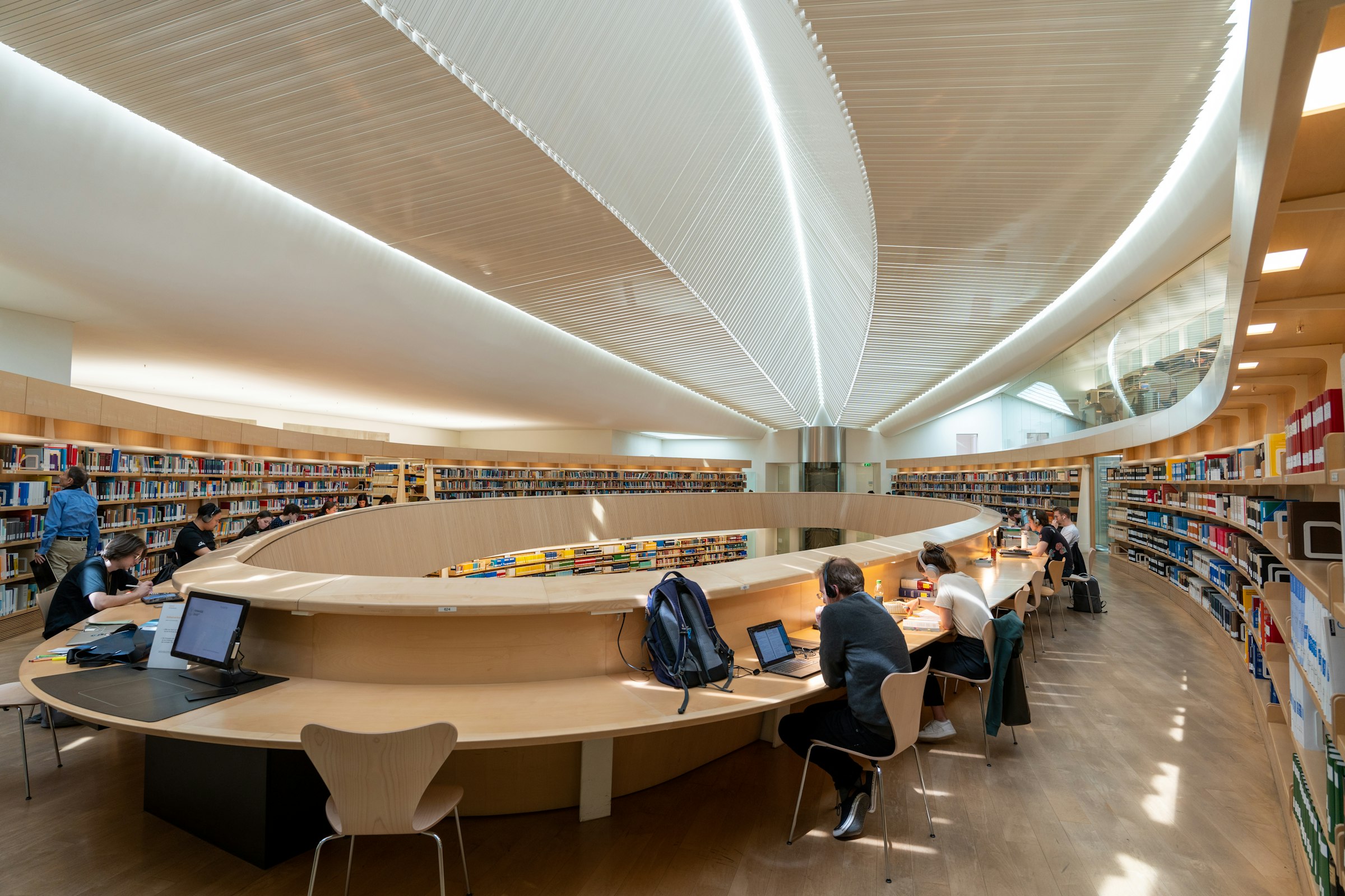 Students working at a curved study desk in a modern library